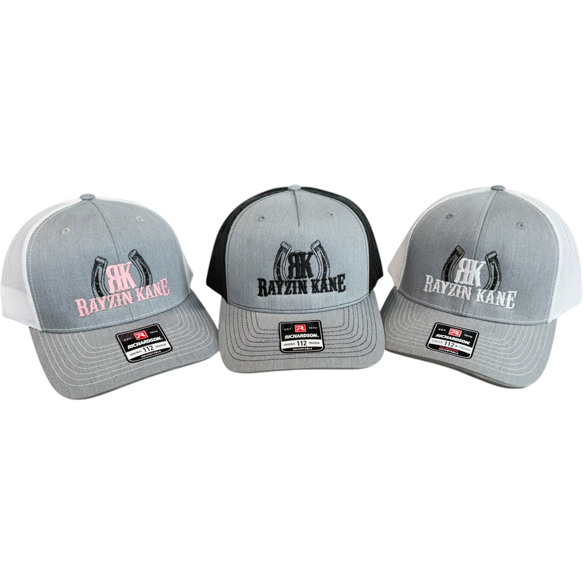 My Store Rayzin Kane Richardson 112 trucker hats in grey with pink, black, and white embroidery on a wooden fence.
